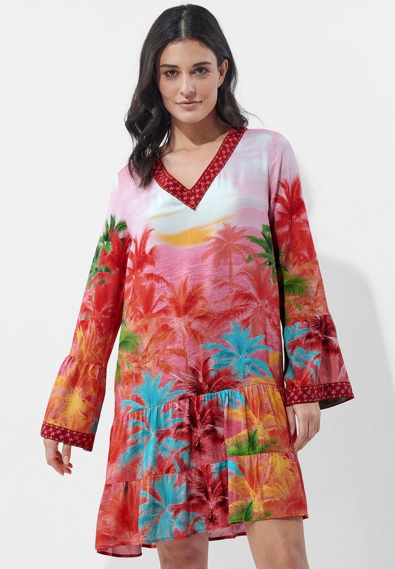 Rotes und pinkes Kleid mit tropischem Palmenbaumdruck, v-Ausschnitt, Glockenärmeln und gestuften Rüschen. Dekorativer roter Rand um den Ausschnitt.