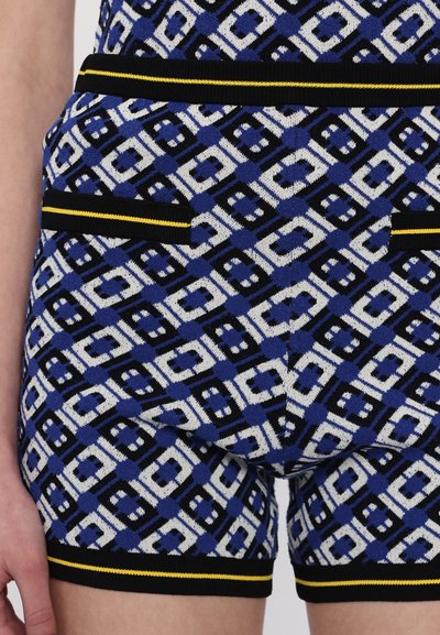 Shorts en tricot avec un motif géométrique en bleu, noir et blanc, dotés d'une taille à rayures noire et jaune et de détails de poches.