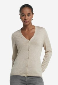 Ljusbeige kofta i mjukt material, med djup V-ringning, knäppning fram och långa ärmar med en figursydd design.