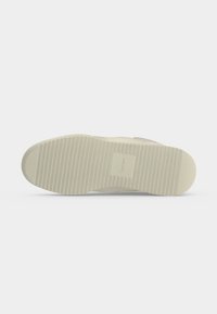 Semelle de chaussure Calvin Klein beige clair avec des rainures horizontales et un motif carré de marque au centre sur fond blanc.