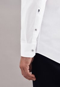 Witte dress shirt kraag met een zwart geborduurd rozenmotief, voorzien van zilveren knopen en een gladde, gestructureerde stof.