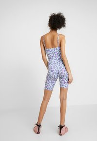 Lepardmönstrad enhetsoverall i lila, blå och gröna toner. Har en figurnära design med tunna remmar och ett slankt, stretcht tyg.