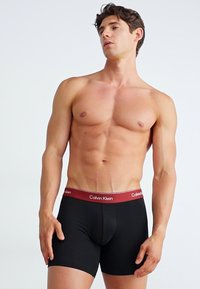 Zwarte boxershorts met een brede rode tailleband met het "Calvin Klein" logo, strakke pasvorm en zachte stoftextuur voor comfort.