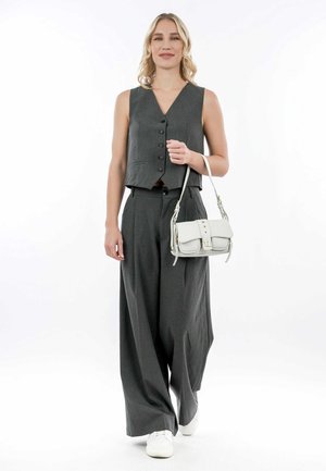 Gilet grigio con bottoni, pantaloni larghi grigi abbinati e scarpe da ginnastica bianche. Borsa bianca con pattina e borchie decorative.