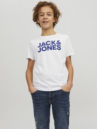 Camiseta de algodón blanca con "JACK & JONES" impreso en letras azules en negrita, combinada con jeans de un azul oscuro. El corte es casual y relajado.