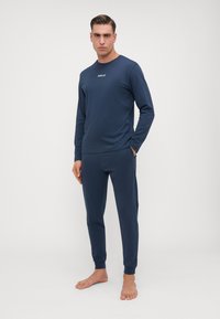 Set de lounge din două piese de culoare albastru închis, fabricat dintr-un material moale. Bluză cu mâneci lungi și logo-ul "REPLAY" și pantaloni de tip jogger cu manșete.