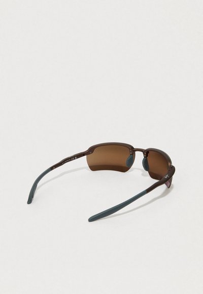 Brown semi-rimless sunglasses with curved gray temples and brown tinted lenses resting open on a white surface.