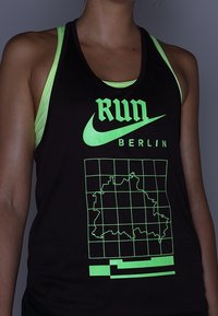 Musta toppi, jossa on neonvihreitä yksityiskohtia. Edessä "RUN" ja "BERLIN" -teksti, ruudukko-kuvio sekä karttaluonnos.