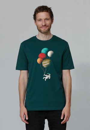 Donkergroene katoenen t-shirt met een astronautengrafiek die kleurrijke planetenballonnen vasthoudt in verschillende tinten en structuren.