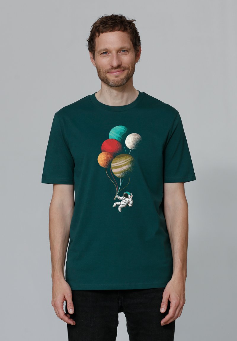 T-shirt en coton vert foncé avec un graphique d'astronaute tenant des ballons de planètes colorées dans différentes teintes et textures.