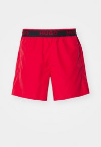 Shorts rouges avec une taille élastique noire portant le logo "HUGO" en rouge. Fabriqués en matière lisse et légère avec un design simple et moderne.