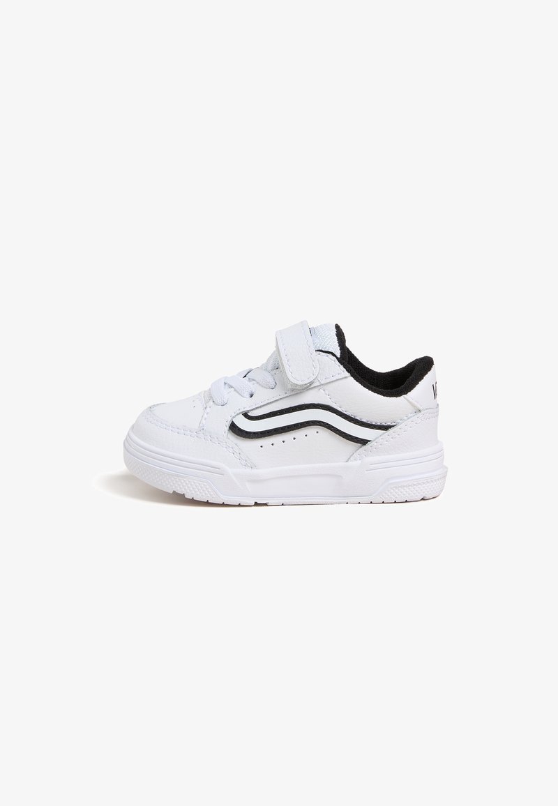 Basket blanche pour tout-petit avec une bande ondulée noire, une bride en velcro, des lacets et une semelle texturée sur fond blanc.