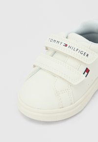 Λευκό αθλητικό παπούτσι Tommy Hilfiger με διπλά λουριά Velcro και λογότυπο στο λουράκι και στο πλάι, με ελαφρώς υφασμένο εσωτερικό επένδυση.