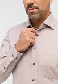 Lichtroze shirt met een rasterpatroon, met knoopsluiting bij de kraag en blauwe knopen. Heeft een borstzak en een gestructureerde stof.