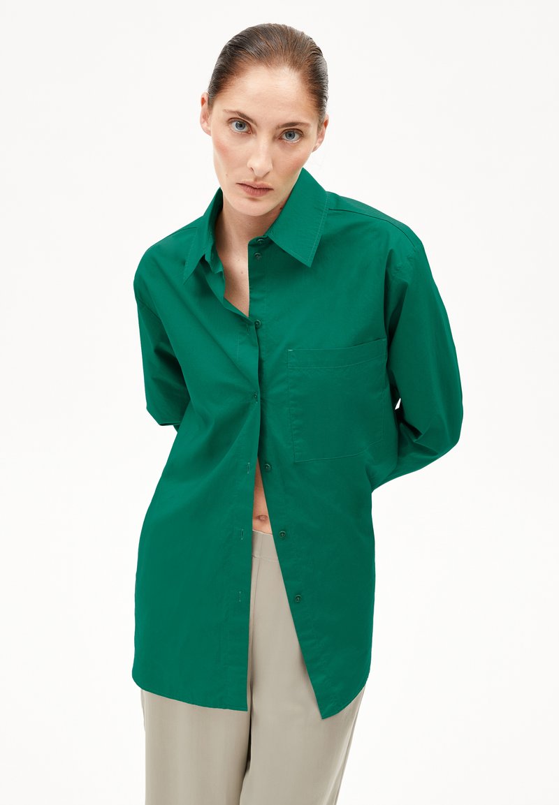Camicia verde a maniche lunghe con colletto a punta, taschino sul petto e vestibilità comoda; realizzata in un tessuto leggero e liscio.