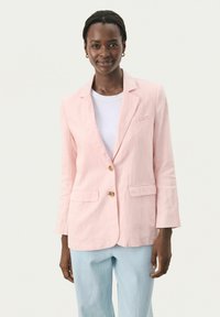 Svetloružový ľanový blazer s dvoma prednými vreckami a uzatvorením na jeden gombík. Nosený na bielom tričku, skombinovaný so svetlo modrými nohavicami.