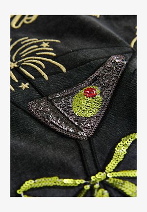 Svart tyg med ett intrikat paljettdesign föreställande ett cocktailglas med en grön oliv och röd accent, prytt med detaljer i guldtråd.