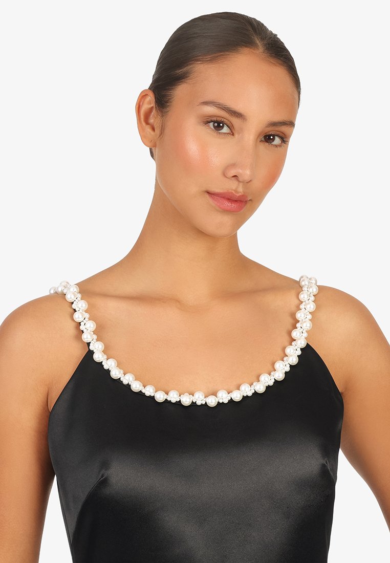 Schwarzes Satin-Kleid mit quadratischem Ausschnitt, verziert mit großen weißen Kunstperlen entlang des Saums. Glatte Textur und elegantes Design.