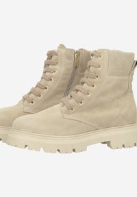 Beige Wildleder-Stiefeletten mit klobiger Sohle, goldfarbenen Beschlägen, Schnürverschluss vorne und seitlichem Reißverschluss für einfaches An- und Ausziehen.