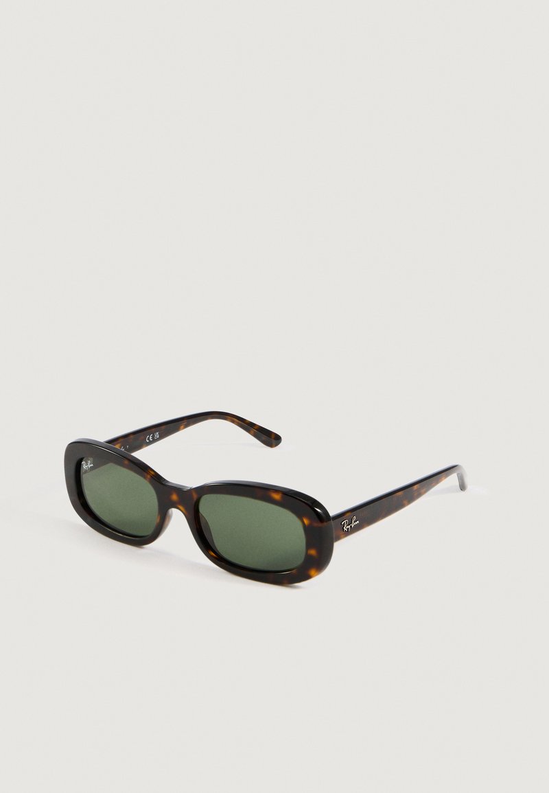 Gafas de sol Ray-Ban de marco rectangular de carey con lentes verdes, inclinadas sobre un fondo claro y liso.