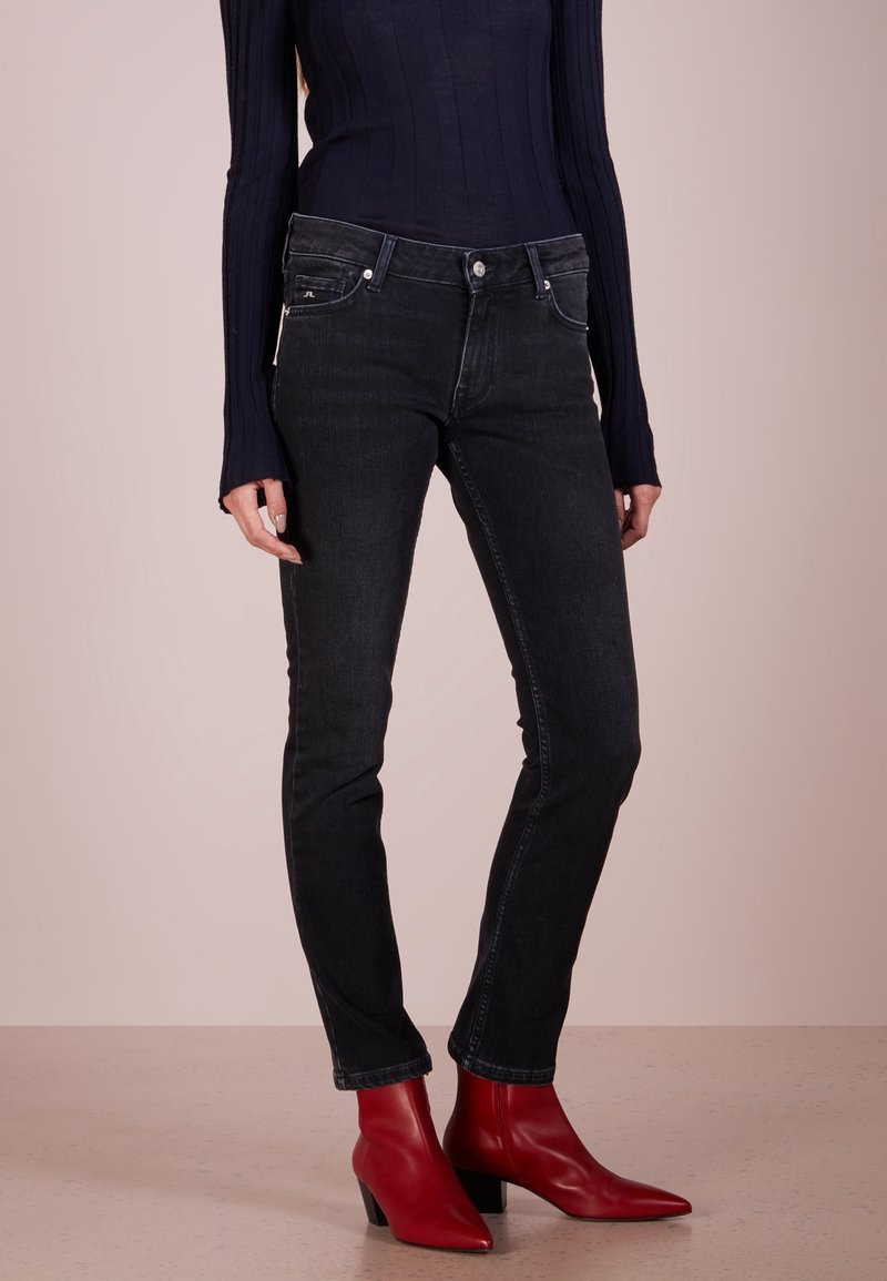 Svarta skinny jeans med medelhöjd, fem fickor och lätt stretch. Matchas med en åtsittande marinblå ribbad tröja och röda ankelboots.