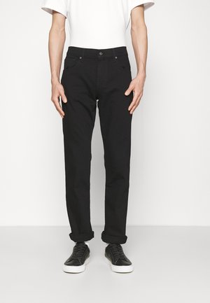 Zwarte jeans met een recht model, vijf-pocket ontwerp en een knoopsluiting, gecombineerd met zwarte sneakers en een wit T-shirt.