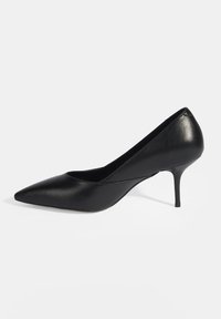 Chaussure à talon haut en cuir noir avec un bout pointu, texture lisse et un talon aiguille effilé. Design minimaliste sans ornements visibles.