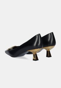 Tacones altos de cuero negro con punta afilada. Presentan un acento en tono dorado en el empeine y tacones cuadrados dorados. Textura suave.