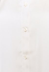 Weiße Bluse aus glattem, leichtem Stoff, mit einer Knopfleiste vorne und vier klaren Knöpfen, die ein einfaches und sauberes Design unterstreicht.