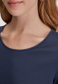 Marineblauwe shirt met een geribbelde textuur en een brede, ronde halslijn, met een mooie stuik langs de randen.