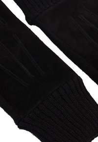 Gants noirs avec une paume en daim et une bordure tricotée. Le design comprend des lignes horizontales sur la paume pour une meilleure prise. Texture lisse sur l'ensemble.
