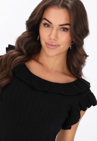 Top negru cu textură ribbed, având un decolteu larg și mâneci scurte cu accente ondulate. Textură netedă și siluetă ajustată.