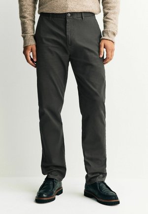 Tmavě šedé chinos kalhoty s plochým předním dílem, poutky na opasek a předními kapsami. Mají jedinečné zapínání na knoflík a jsou vyrobeny z hladké tkaniny.