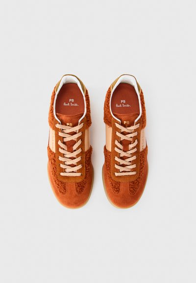 Un paio di sneakers in suede color ruggine con interni in shearling, con lacci beige e branding sulla linguetta e sui lati, viste dall'alto.