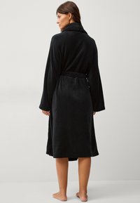 Zwarte fleec bathrobe met een sjaalkraag, lange mouwen en een tailleband. Heeft een zachte textuur en een knielange ontwerp.
