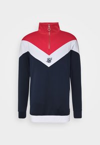 Granatowy sweter z czerwono-białym wzorem w zygzak, z półzipem, wyszywanym logo na klatce piersiowej oraz białym teksturowanym pasem na dole.