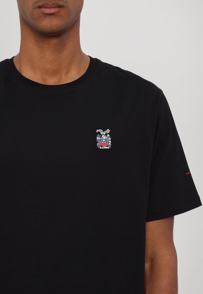 T-shirt en coton noir avec un petit logo brodé sur la poitrine, avec des détails colorés et une texture douce. Manches courtes et col rond.