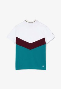 Koszulka z krótkim rękawem z białym kołnierzykiem, bordowym akcentem w kształcie chevronu i tealową teksturowaną dolną częścią z napisem "ULTRA DRY".