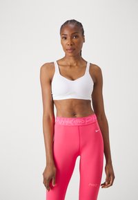 Hvit sports-bh med justerbare stropper og en subtil Nike-logo, kombinert med livlige rosa høyt liv leggings med merket livlinning.