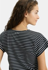 Maglietta a righe bianche e nere con maniche corte, tessuto morbido e un piccolo dettaglio con logo vicino alla scollatura sul retro.