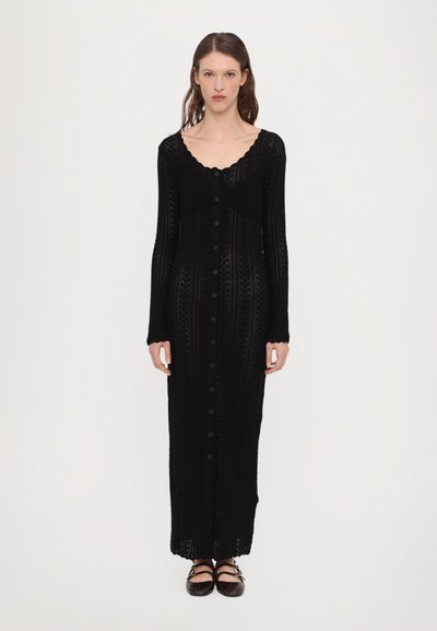 Schwarzes, langärmeliges Strickkleid mit Rundhalsausschnitt, Knopfverschluss vorne und aufwendigen Mustern. Weiche Textur und fließende Silhouette.