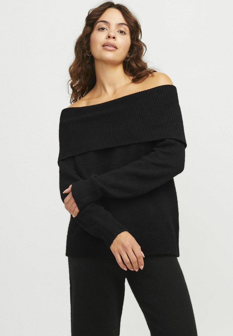 Maglione nero scollato sulle spalle con colletto e polsini a costine, realizzato in un morbido tessuto, abbinato a pantaloni neri coordinati.