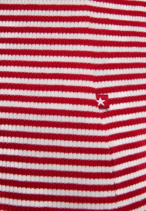 Punane ja valge triibuline kangas, millel on sooneline tekstuur ja väike punane silt valge tähe detailiga.