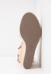Semelle d'une espadrille compensée rose avec grip texturé, talon enveloppé de jute et branding "New Look" avec étiquette de taille 5/38 visible.