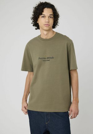 T-shirt en coton vert olive à manches courtes ; présente un texte imprimé "Positive Altitude né pour gravir" et un graphique de montagne simple.