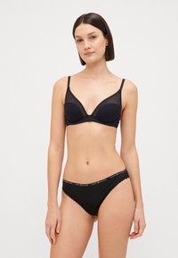 Soutien-gorge noir avec armatures et bordure en dentelle, associé à un slip bikini noir assorti avec une taille de marque. Texture de tissu lisse.