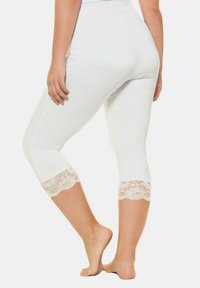 Leggings bianchi con un design aderente, con dettagli in pizzo sul polpaccio, realizzati in tessuto morbido, ideali per il comfort e la facilità nei movimenti.