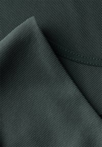 Tessuto texturizzato di colore verde scuro, con un motivo a coste diagonali e un finish liscio. Il tessuto è piegato, mostrando entrambi i strati e le cuciture.