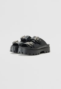 Sandali platform in pelle nera con punta aperta, dotati di due fibbie regolabili, hardware in argento e suola in gomma testurizzata.