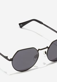 Crne osmerokutne sunčane naočale s tamnim lećama, metalnim okvirom i podesivim jastučićima za nos. Imaju lagan dizajn i elegantne bočne dijelove.